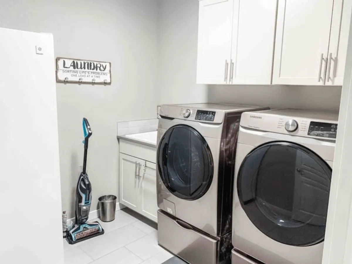 A tidy laundry area with a washer and dryer, a 'Laundry' sign, and a clean countertop, evoking a sense of order and practicality. The space is organized for easy use and daily tasks.