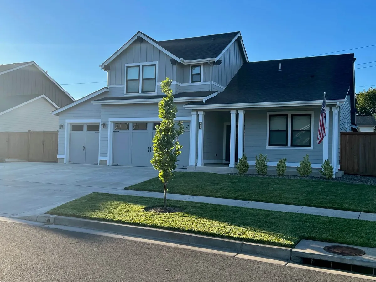 A classic and friendly front porch with symmetrical windows, a landscaped lawn, and an American flag, setting a welcoming tone for arrivals and departures. The inviting exterior hints at the warmth and hospitality awaiting inside.
