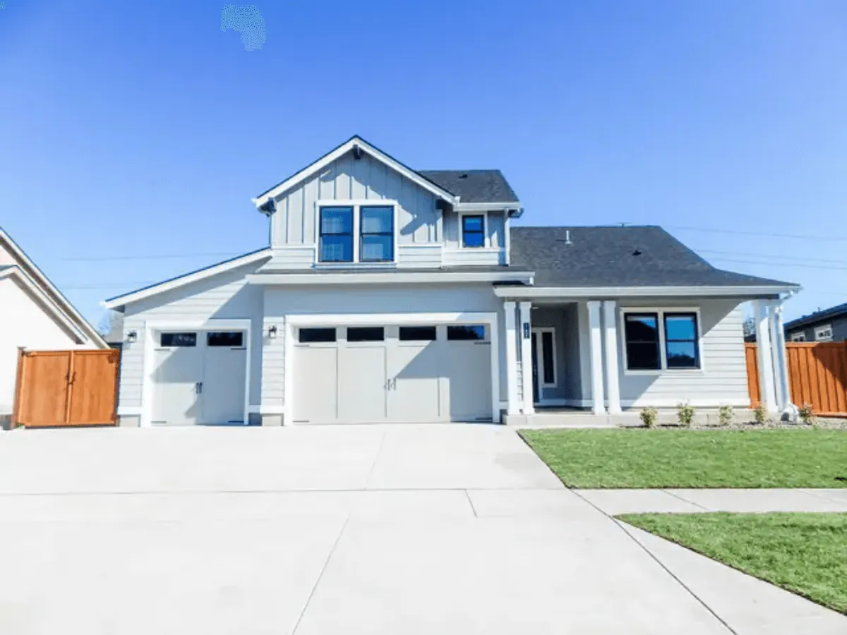 The welcoming front entrance of the home with large windows, a manicured lawn, and a two-car garage. The lively front area is perfect for greeting guests, watching children play on the lawn, or hosting outdoor activities.
