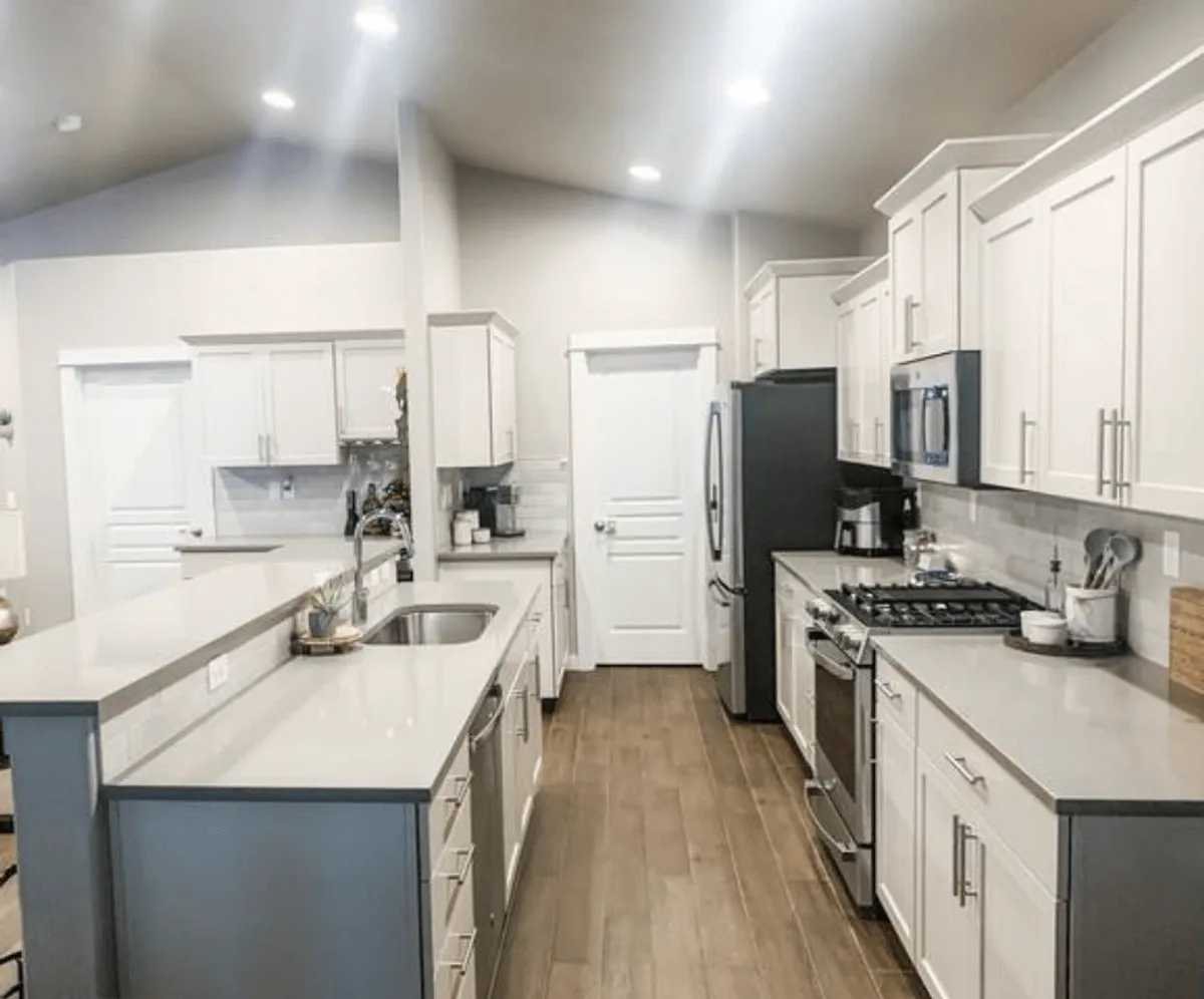 A contemporary kitchen scene featuring a large island countertop, modern cabinetry, and shiny stainless steel appliances. The sink and spacious layout invite both cooking and social gatherings.
